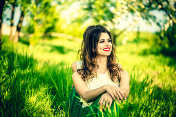 Two happy pretty girls sitting on the green grass