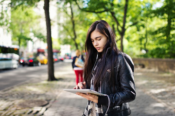 Young brunette woman portrait using tablet in the street. New Yo