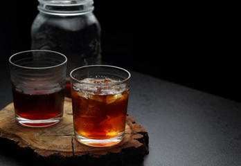Filter coffee in glasses of hot and cold on a wooden board on dark background with copy space.