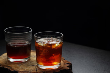Filter coffee in glasses of hot and cold on a wooden board on dark background with copy space.