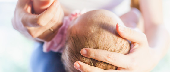 Mother holding baby head at hands