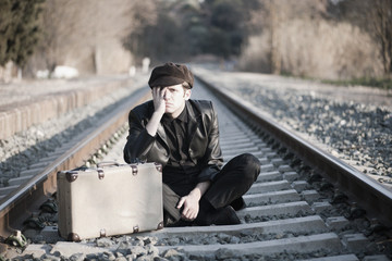 HOMBRE ELEGANTE JUNTO A LAS VIAS DEL TREN CON SOMBRERO Y MALETA