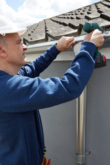 Workman Replacing Guttering On Exterior Of House