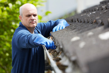Man Clearing Leaves From Guttering Of House © highwaystarz