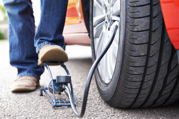 Close Up Of Man Inflating Car Tyre With Foot Pump