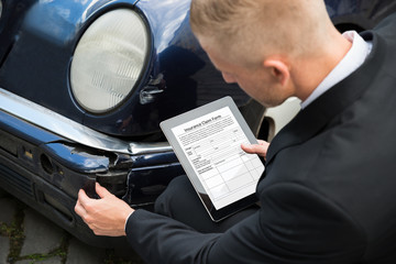 Obraz premium Man Holding Digital Tablet Examining Damaged Car