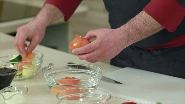 Chef peeling tomatoes after soaking them into the hot water. Close-up