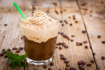 Ice coffee with whipped cream in a glass on the wooden table