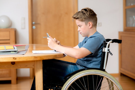 boy in wheelchair doing homework and using tablet pc