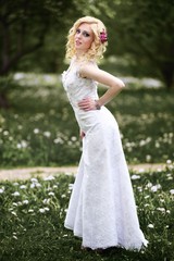 Fototapeta na wymiar Beautiful young bride in white dress in summer green park