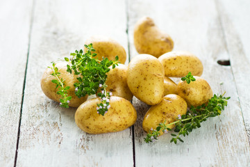 Fresh young potatoes on a wooden background with herbs