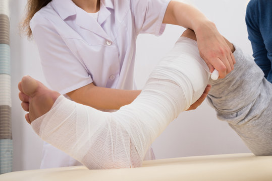 Doctor Bandaging Patient's Leg