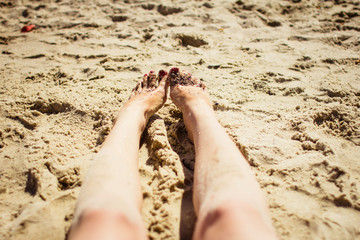 young woman legs sunbathing on the beach