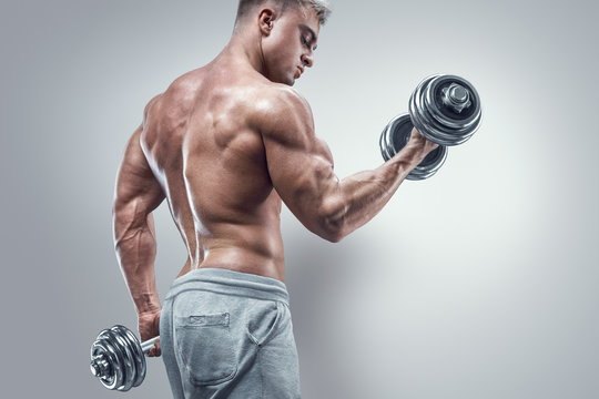 Power Athletic Man In Training Pumping Up Muscles With Dumbbells