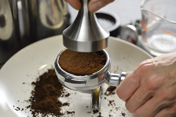 Barista using a tamper to press ground coffee into a portafilter