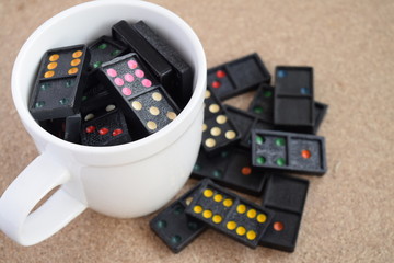 Black Dominoes in coffee cup on wooden background