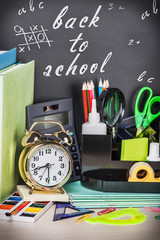 school supplies on the desk in the background of chalkboard