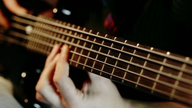 Musician playing five string electric bass guitar; cluseup