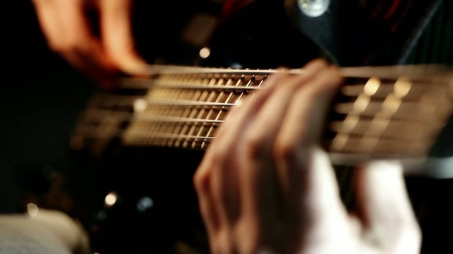 Musician playing bass guitar; closeup, zoom in; 