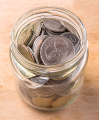 Malaysian coins in a mason jar over wooden background