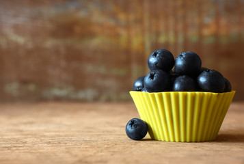 Fresh Blueberry in the Yellow Cup on Wooden as Background.