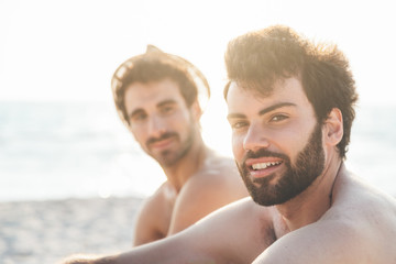 Couple male friends on the beach at sunset