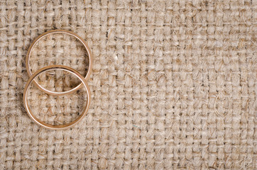 Two gold wedding rings lying on brown cloth sacking