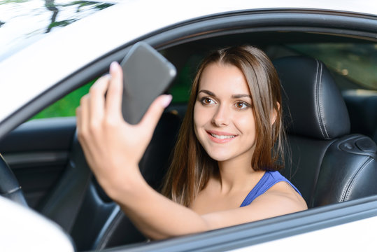 Pleasant woman doing selfie inside car