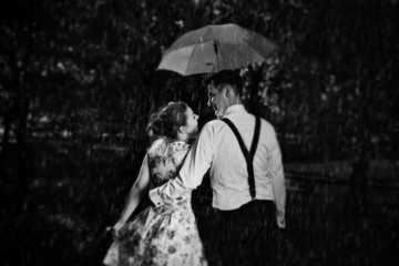 Young romantic couple in love flirting in rain. Black and white