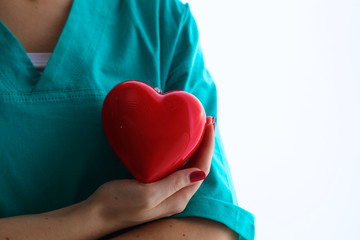 Female doctor with stethoscope holding heart over white