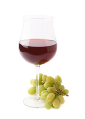 Glass of red wine next to a branch of grapes
