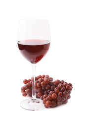 Glass of red wine next to a branch of grapes