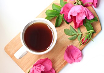 Fototapeta na wymiar white cup on wooden tray healthy herbal rose hip tea fresh flowers 
