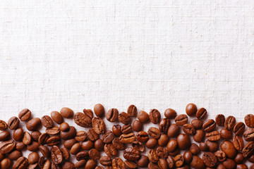 Frame of coffee beans on color sackcloth background