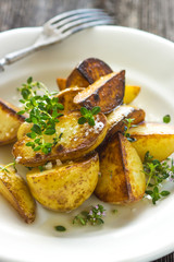 Baked new potatoes with herbs on a wooden background