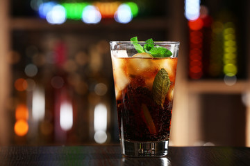 Glass of cocktail in bar on bright blurred background