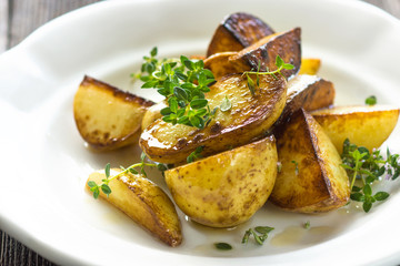 Baked new potatoes with herbs on a wooden background