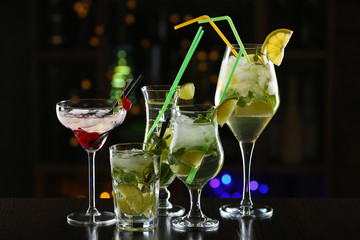 Glasses of cocktails on bar background