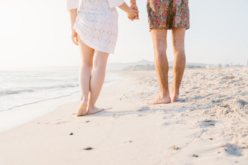 Loving couple walking on the beach at sunset