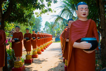 Sculptures of priests in red clothes, in the hands of the bowl.Siemreap,Cambodia.