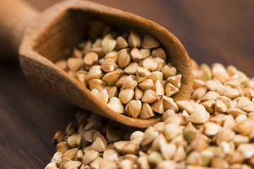 Buckwheat with a spoon on a wooden boards background
