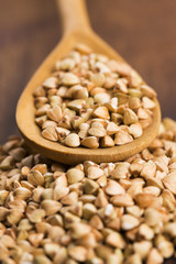 Buckwheat with a spoon on a wooden boards background