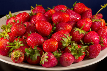 Close up of juicy garden strawberries on a white plate