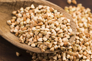 Buckwheat with a spoon on a wooden boards background