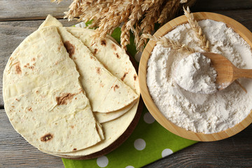 Stack of homemade whole wheat flour tortilla on cutting board, on wooden table background
