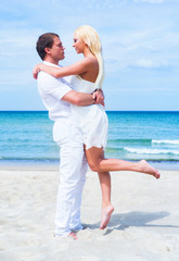Loving couple walking and embracing on a tropical summer beach