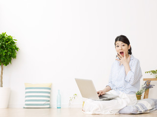 部屋でノートパソコンを使う女性　驚く