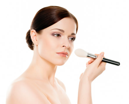 Beauty portrait of young, attractive, fresh, healthy and natural woman holding a makeup brush isolated on white