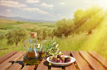Olive oil and olives and on the wooden table against Tuscan land