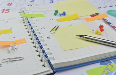 Pen with post It notes and pin on business diary page